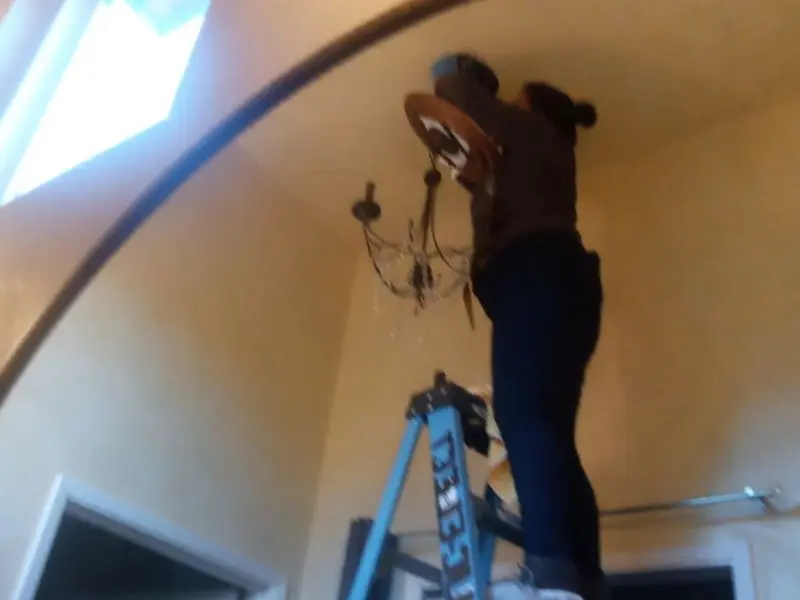 Electrician installing a chandelier in a Joppatowne residence